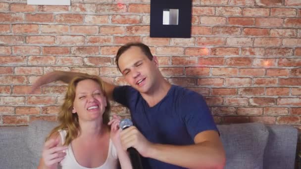 Paar zingen lied - karaoke team. paar man en vrouw zingen liederen in een microfoon die zittend op de Bank. 4k, slow-motion — Stockvideo