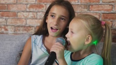 iki küçük kız mikrofona şarkı söylüyorlar. ev karaoke şarkılar. 4 k, yavaş hareket, yakın çekim