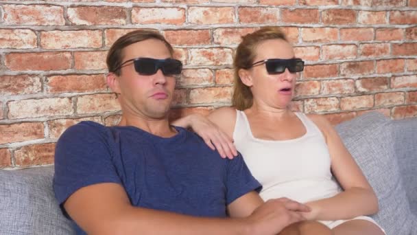 Закрывай. молодая пара в очках 3d, сидя на диване в гостиной со многими эмоциями, смотреть фильм. 4k, slow motion . — стоковое видео