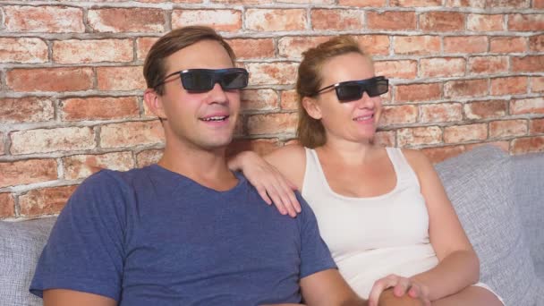 Fecha. um jovem casal em óculos 3d, sentado no sofá na sala de estar com muitas emoções, assistir o filme. 4k, câmera lenta . — Vídeo de Stock