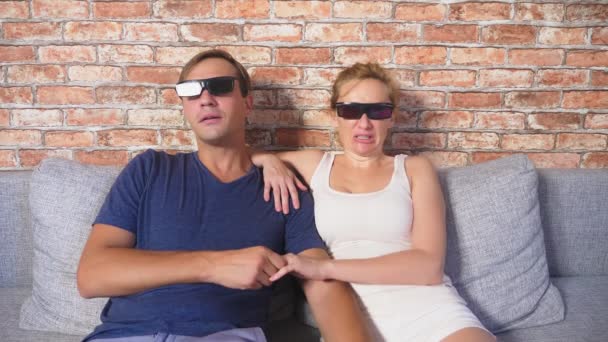 닫습니다. 젊은 부부의 3d 안경, 영화를 보고, 많은 감정 거실에서 소파에 앉아. 4 k, 슬로우 모션. — 비디오