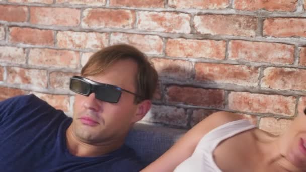 Gros plan. un jeune couple en 3d lunettes, assis sur le canapé dans le salon avec beaucoup d'émotions, regarder le film. 4k, au ralenti . — Video