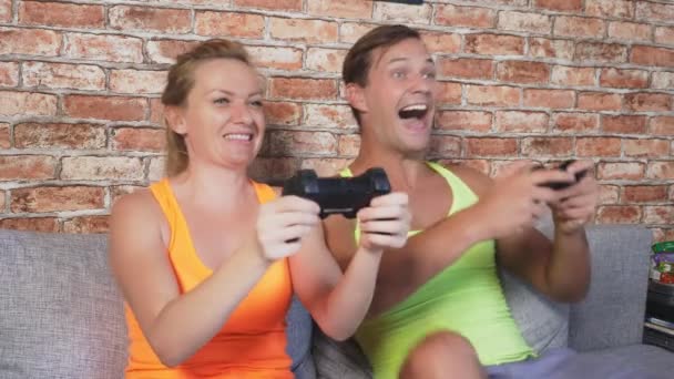 Emocjonalne mężczyzna i kobieta grać joysticki w konsoli, konkurować i zrobić szalony twarze śmieszne. 4k, zwolnionym tempie — Wideo stockowe
