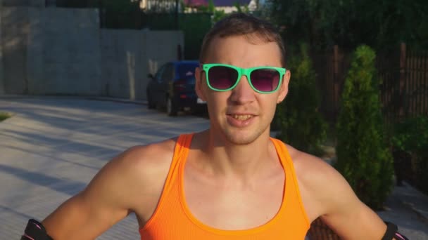 Sexy glücklicher Kerl in heller Kleidung, der auf seinen Rollschuhen posiert. Langsames Video, 4k, Standbild — Stockvideo