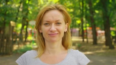 bir alışveriş merkezi üzerinde bir parkta duran genç bir mavi gözlü kadın portresi. 4. ağır-çekim çekim.