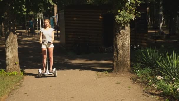 Девушка в белых шортах, ездит на Сигвее в ясный солнечный день. летний парк и солнечный свет. 4к, замедленная съемка, stadibshot — стоковое видео