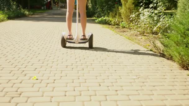 Девушка в белых шортах, ездит на Сигвее в ясный солнечный день. летний парк и солнечный свет. 4к, замедленная съемка, stadibshot — стоковое видео
