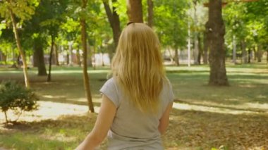 Yaz günü güneş ışığı altında onun telefon ile park olacak kadın. 4 k, yavaş hareket, standicam atış