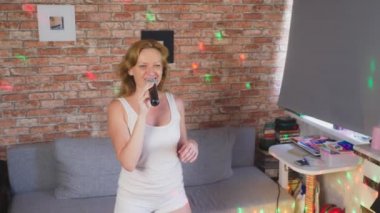Yakın çekim. bir kadın çığlığı için bir mikrofon. bir kadın bir ev ortamında bir mikrofona karaoke şarkı söylüyor. 4k, ağır çekim