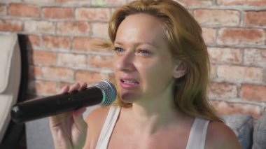Yakın çekim. bir kadın çığlığı için bir mikrofon. bir kadın bir ev ortamında bir mikrofona karaoke şarkı söylüyor. 4k, ağır çekim