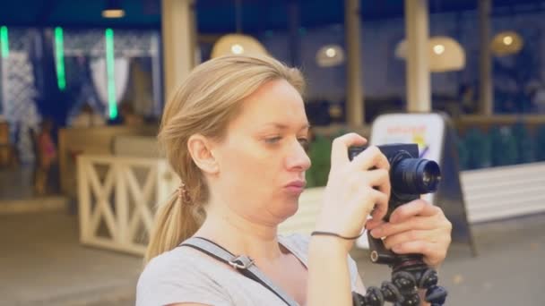 Photographe professionnel, prend des photos dans un parc d'attractions, une femme appuie sur un bouton d'un gadget dans un jardin fleuri. 4k, ralenti, tir steadicam — Video