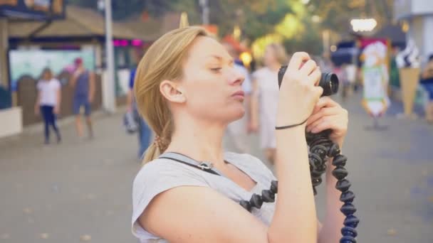 プロのカメラマンは、遊園地で写真を撮る、女性は花の咲く庭園の間でガジェットのボタンを押した。4 k、スローモーション、ステディカム撮影 — ストック動画