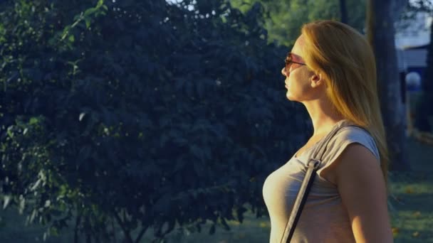 Portrait d'une jeune femme aux yeux bleus debout dans un parc sur un centre commercial. 4. Prise de vue au ralenti . — Video