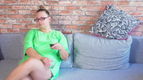 Ung, uttråkad kvinna tittar på Tv sitter på soffan hemma. 4k — Stockvideo