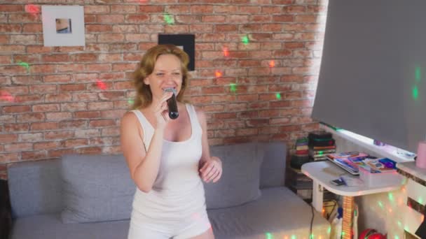 Närbild. en kvinna som skrek till en mikrofon. en kvinna sjunger karaoke i en mikrofon i hem miljö. 4k, Slowmotion — Stockvideo