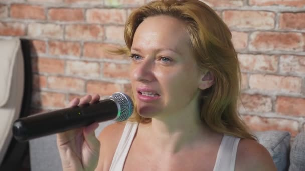 Κοντινό πλάνο. μια γυναίκα ουρλιάζοντας σε ένα μικρόφωνο. μια γυναίκα τραγουδάει karaoke σε ένα μικρόφωνο σε ένα εγχώριο σκηνικό. 4k, αργή κίνηση — Αρχείο Βίντεο