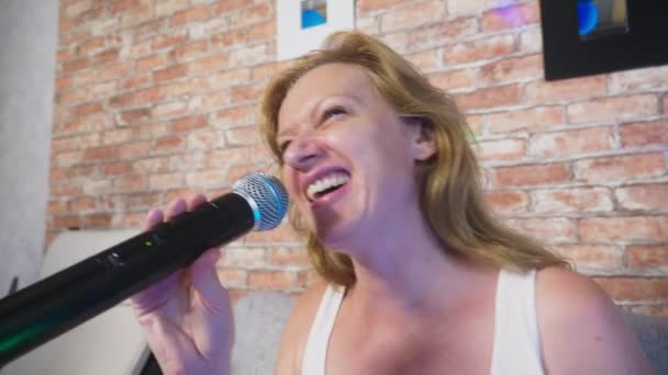 Fecha. uma mulher a gritar para um microfone. uma mulher canta karaoke em um microfone em um ambiente doméstico. 4k, câmera lenta — Vídeo de Stock