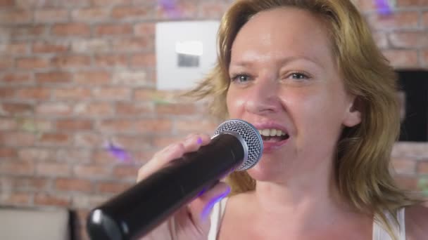 De cerca. una mujer gritando a un micrófono. una mujer canta karaoke en un micrófono en un entorno familiar. 4k, cámara lenta — Vídeo de stock