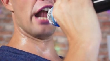 deli, komik ve genç bir adam, bir mikrofona şarkı söylüyor. yakın çekim. 4k, ağır çekim.