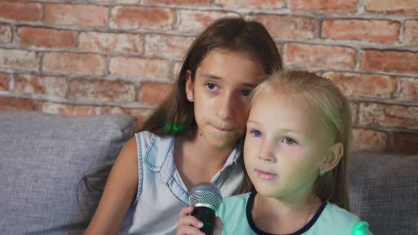 Two little girls are singing into the microphone. songs in home karaoke. 4k, slow-motion, close-up — Stock Video