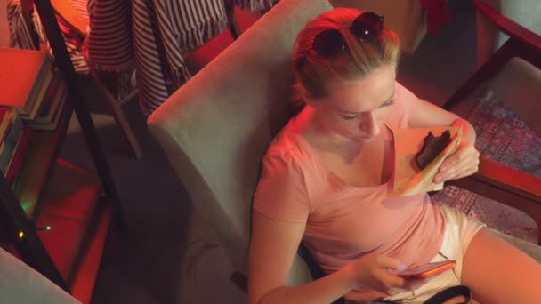 La ragazza sta bevendo un caffè con un biscotto in un caffè retrò e navigando attraverso il suo telefono. 4K. Rallentatore — Video Stock