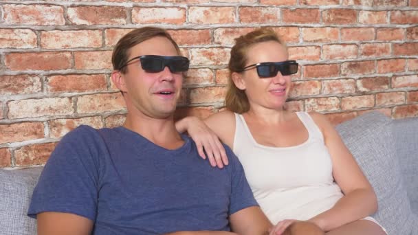 De cerca. una joven pareja en gafas 3d, sentado en el sofá en la sala de estar con muchas emociones, ver la película. 4k, cámara lenta . — Vídeos de Stock