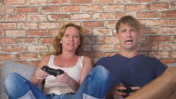 感情的な男と女性再生ジョイスティックのコンソールで、彼らは競争し、狂気の面白い顔を作る。4 k、スローモーション — ストック動画