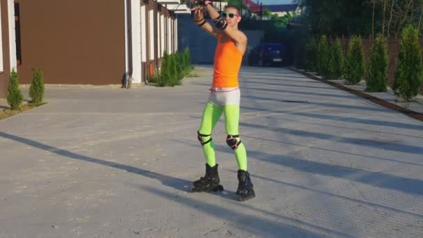 Sexy happy guy in bright clothes, doing poses on his roller skates. Slow video, 4k, standicam shot — Stock Video