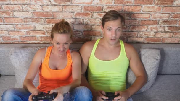 情绪化的男人和女人在控制台上玩游戏杆, 他们竞争并制造出疯狂可笑的面孔。4k. 慢动作 — 图库视频影像