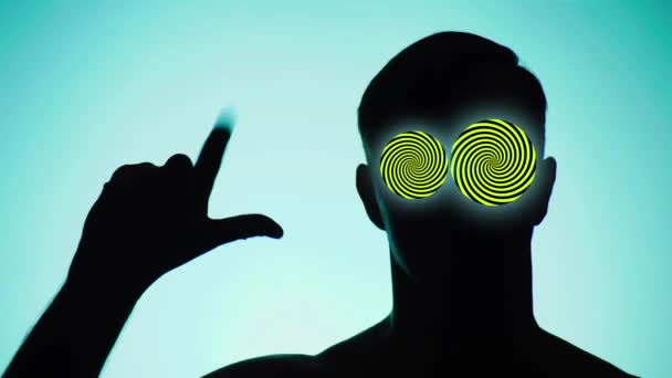 Background color. 4k, slow motion. shadow of a person. the guy shows gesture, the score on the fingers to five, in place of his eyes hypnotic circles — Stock Video
