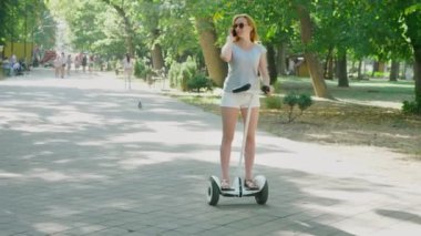 Yaz günü güneş ışığı altında onun telefon ile park olacak kadın. 4 k, yavaş hareket, standicam atış