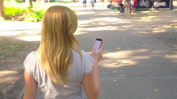 Donna che va a parcheggiare con il suo telefono al giorno d'estate sotto la luce del sole. 4k, rallentatore, ripresa standicam — Video Stock