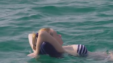 kalıcı makyaj dinlenme olmadan bir kadın. Bir kızın sırtında bir şişme yastık üzerinde yalan denizde yüzüyor. 4 k yavaş hareket