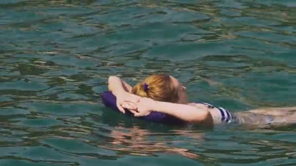 メイクアップ休憩なしの女性。女の子がインフレータブル枕横になっている背中に海で浮かんでいます。4 k スローモーション — ストック動画