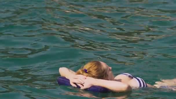 Kobieta bez makijażu odpoczynku. Dziewczyna jest pływające w morzu na plecach lezy na nadmuchiwaną poduszką. 4 k zwolnionym tempie — Wideo stockowe