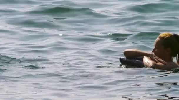 Een vrouw zonder make-up rusten. Een meisje is op haar rug liggend op een opblaasbaar kussen in de zee drijven. 4 k slow-motion — Stockvideo