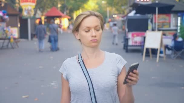 Donna che va a parcheggiare con il suo telefono al giorno d'estate sotto la luce del sole. 4k, rallentatore, ripresa standicam — Video Stock