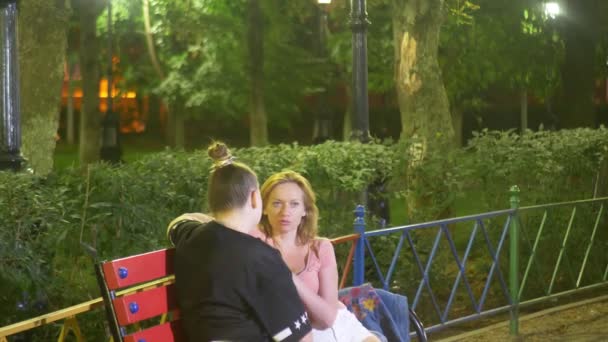 2 人の女性は、暖かい夏の夜の公園を散歩、彼らの問題について話します。通りのガール フレンドを夜に待ち合わせ、ステディカム撮影。4 k, — ストック動画