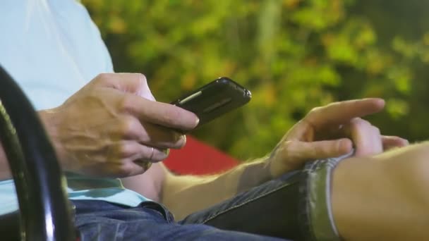 Привабливий сумний чоловік сидить на лавці зі смартфоном. пізно в теплу літню ніч. в парку. 4k, стайка постріл — стокове відео