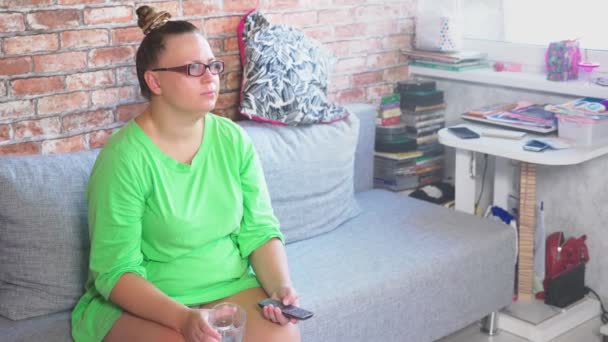 Jeune femme ennuyeuse regardant la télévision assise sur le canapé à la maison. 4k — Video