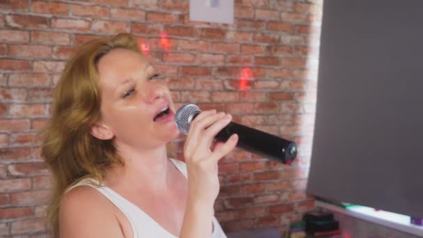 Fecha. uma mulher a gritar para um microfone. uma mulher canta karaoke em um microfone em um ambiente doméstico. 4k, câmera lenta — Vídeo de Stock