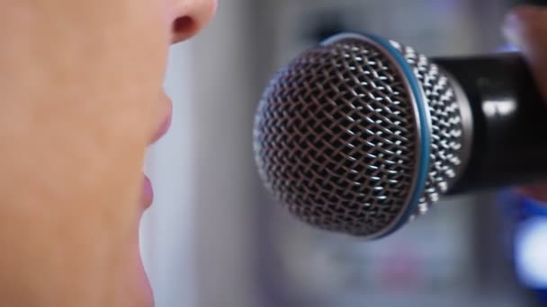 Zblízka. žena křičí do mikrofonu. žena zpívá karaoke do mikrofonu v domácím prostředí. 4k, pomalý pohyb — Stock video