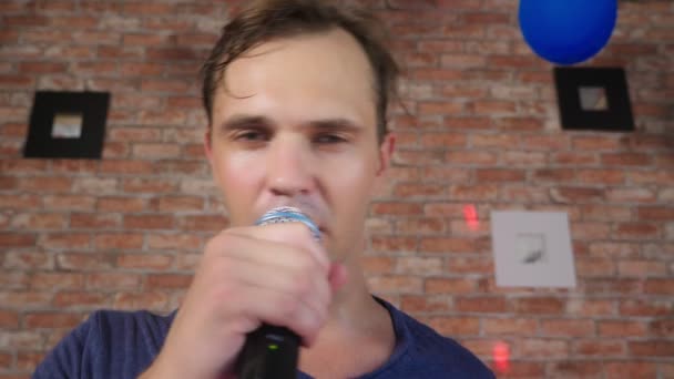 Egy őrült vicces fiatalember dalokat énekel a mikrofonba. közelről. 4k, lassú mozgás. — Stock videók