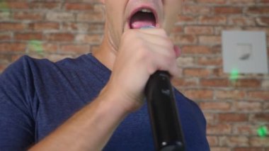 deli, komik ve genç bir adam, bir mikrofona şarkı söylüyor. yakın çekim. 4k, ağır çekim.