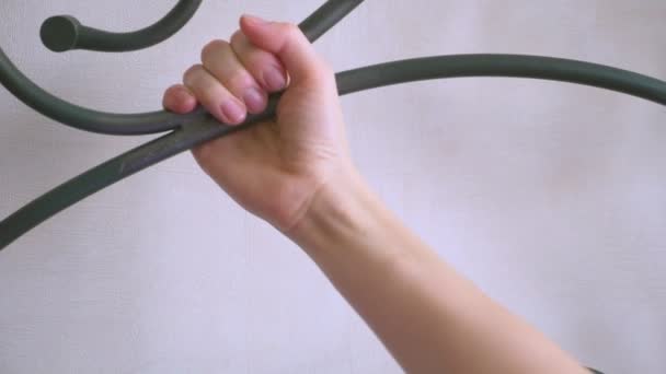 女性の手がベッドの鍛造ヘッドにしがみついて。鍛造ベッド、詳細。4 k、スローモーション. — ストック動画