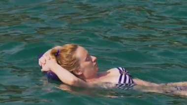 kalıcı makyaj dinlenme olmadan bir kadın. Bir kızın sırtında bir şişme yastık üzerinde yalan denizde yüzüyor. 4 k yavaş hareket