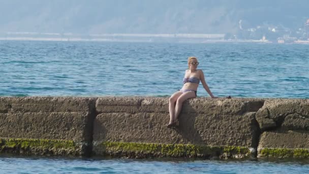 Vista de las islas en la bahía. Telefoto disparado. mujer en el rompeolas mira a la orilla del mar en la niebla, 4k, cámara lenta — Vídeo de stock