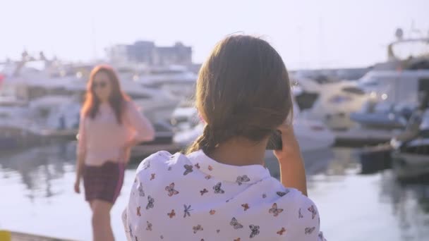 プロのカメラマン、写真背景にヨットの港で女性ボタンを押すし、モデルに話しかけます。4 k、スローモーション, — ストック動画