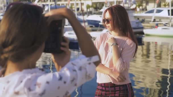 Профессиональный фотограф, фотографии в морском порту на фоне яхт, женщина нажимает кнопку и разговаривает с моделью. 4k, slow motion , — стоковое видео