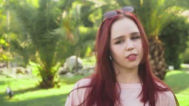 parkta dans genç güzel kızıl saçlı kız. tropikal bir parkta avuç içi bir arka plan üzerinde dans mini etek kadında. 4k, ağır çekim